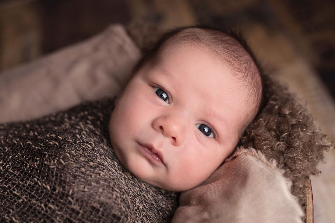 Close-up portrait of a wide-eyed newborn baby